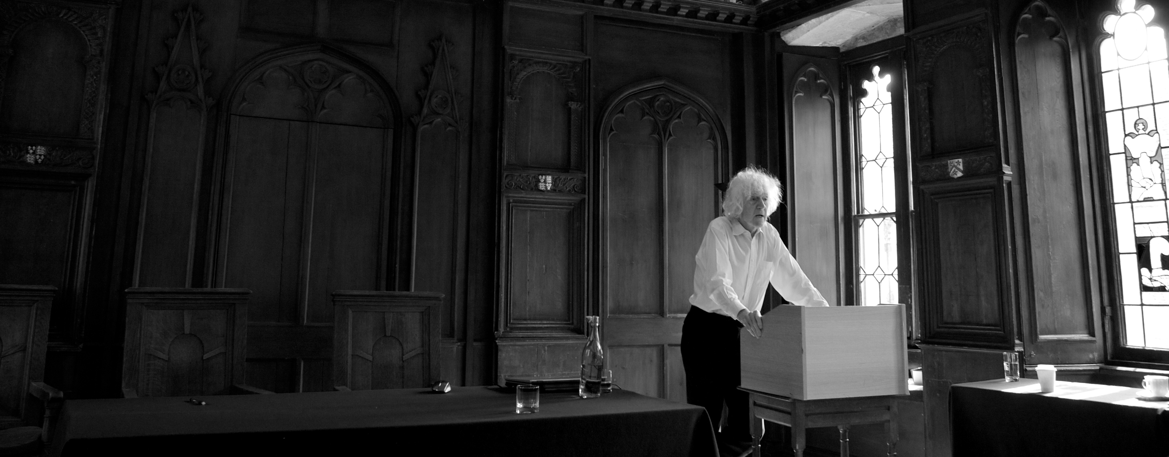 Derek Parfit at the lectern in the wood-paneled hall of All Souls College
